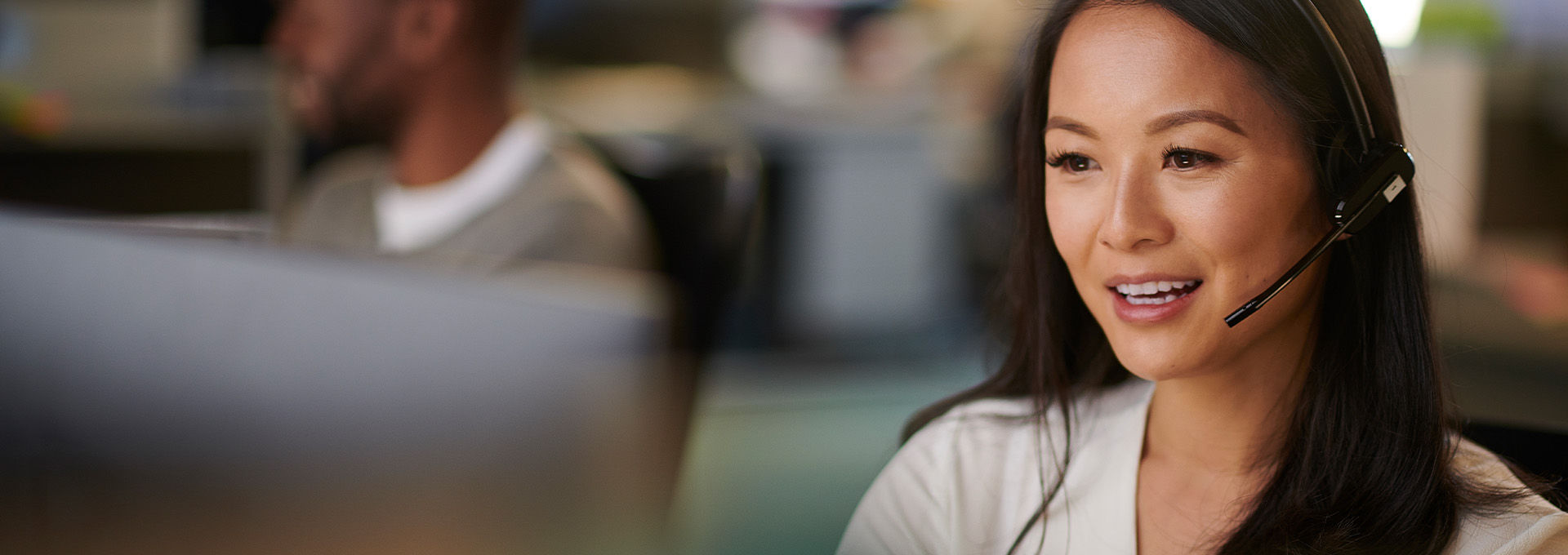 Woman in an office wearing a phone headset using a computer