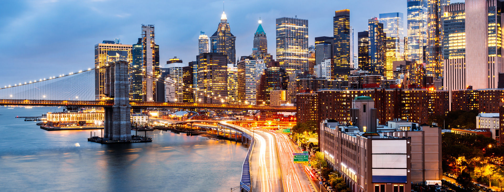 Brooklyn Bridge and East River of New York City illuminated at dusk